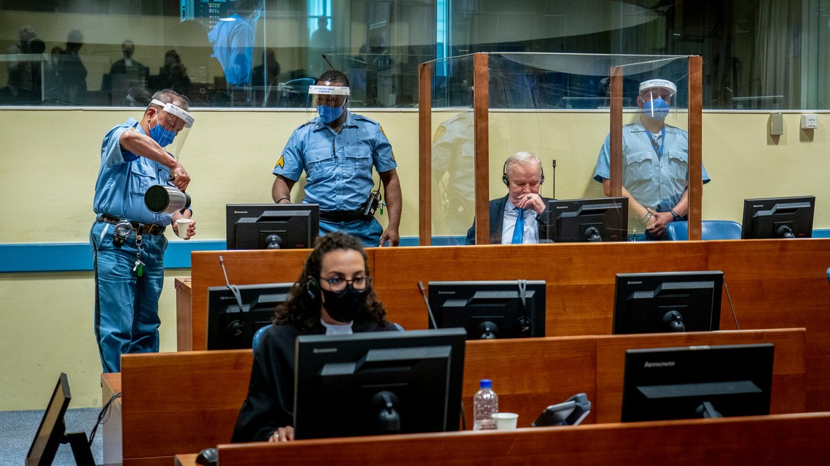 Ratko Mladić, früherer General und verurteilter Kriegsverbrecher, im Gerichtsgebäude in Den Haag am 08.06.21 - umgeben von Justizmitarbeitern.