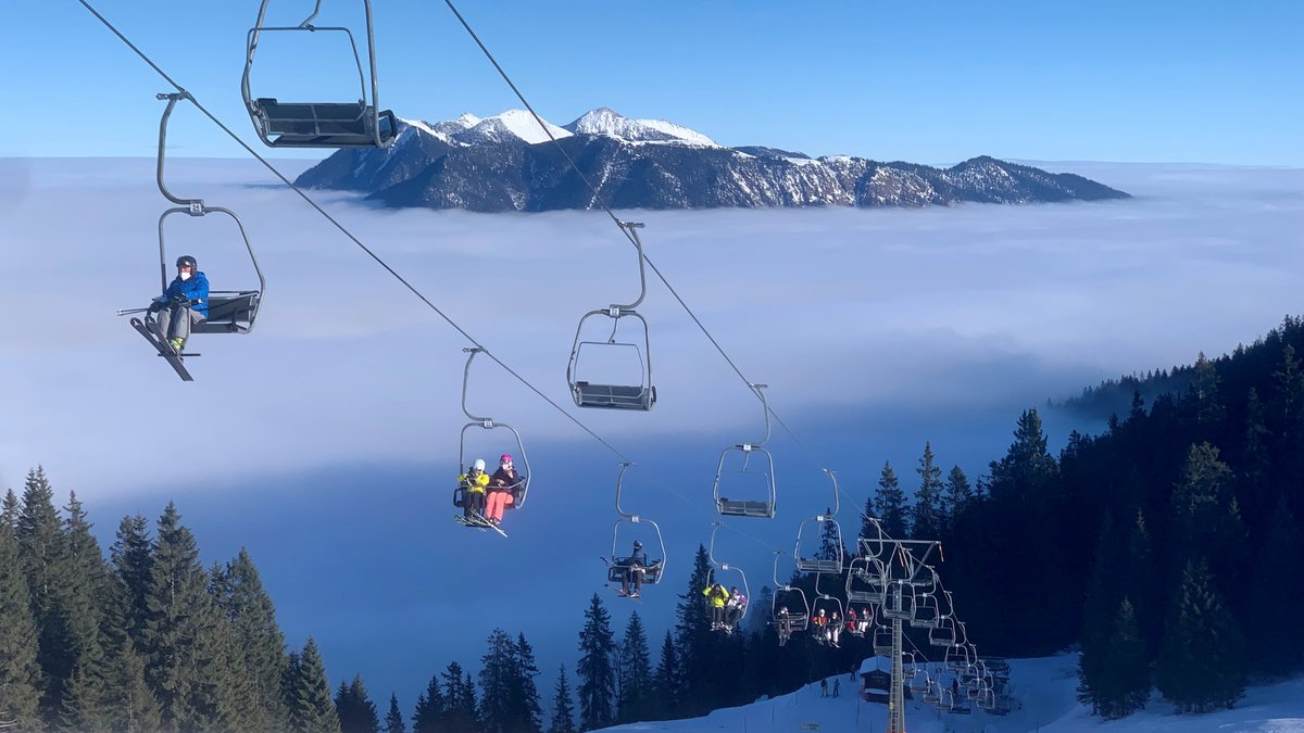 In einer Sesselbahn am Kreuzeck bei Garmisch-Partenkirchen fahren die ersten Skifahrer der Saison auf den Berg.