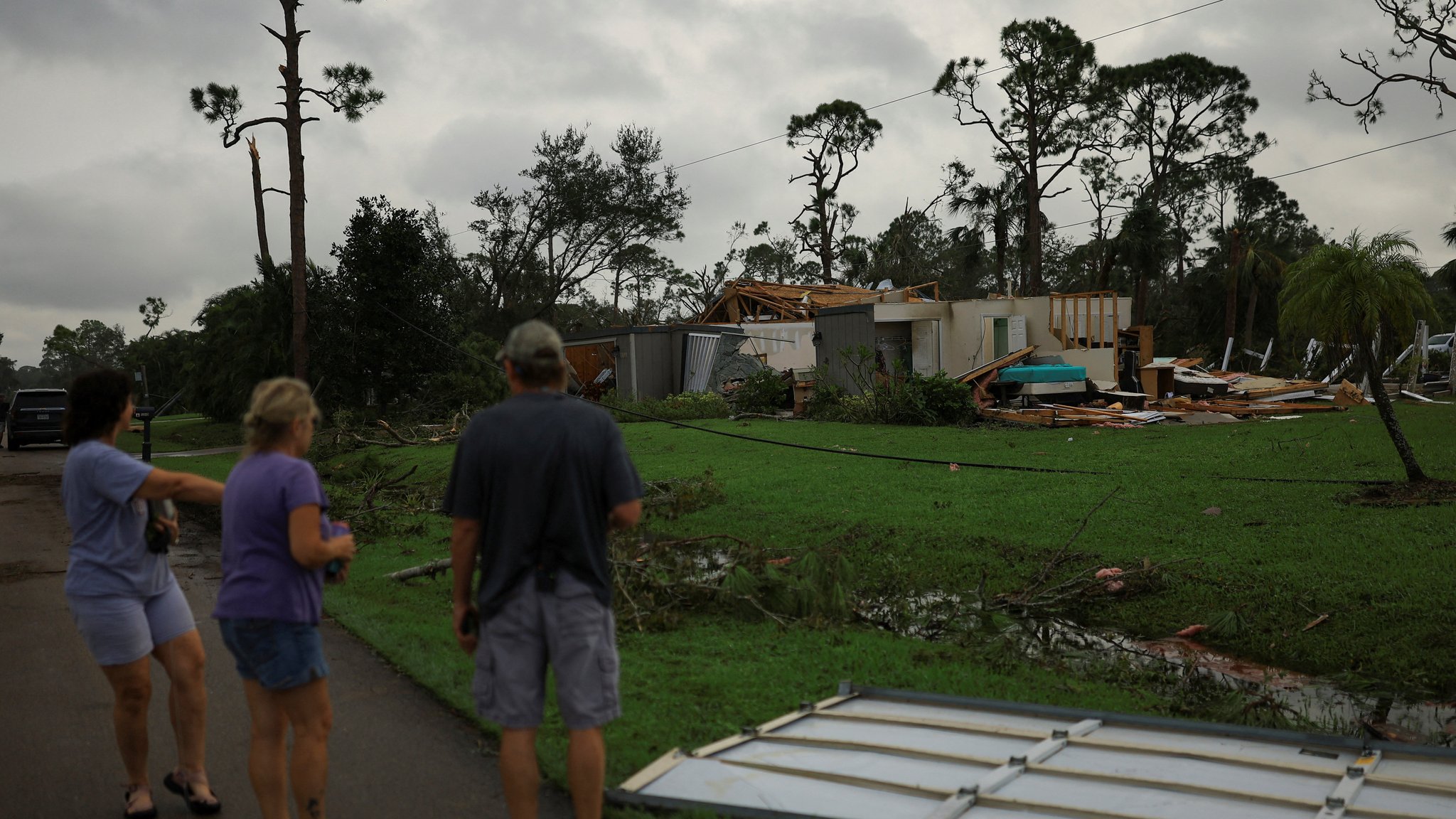 Menschen schauen auf zerstörte Häuser in Lakewood Park, nahe Fort Pierce, in St. Lucie County, Florida