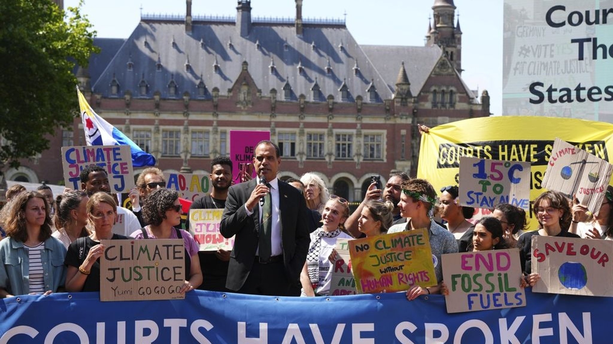 23.07.2025, Niederlande, Den Haag: Ralph Regenvanu (M), Vanuatus Minister für Klimawandel, spricht umringt von Demonstranten, vor dem Internationalen Gerichtshof. Der Internationale Gerichtshof soll im Auftrag der UN-Generalversammlung ein Rechtsgutachten erstellen zur Frage, inwieweit Staaten rechtlich zum Klimaschutz verpflichtet sind und inwieweit sie für die von ihnen durch den Ausstoß von Treibhausgasen verursachten Schäden verantwortlich gemacht werden können. Foto: Peter Dejong/AP/dpa +++ dpa-Bildfunk +++
