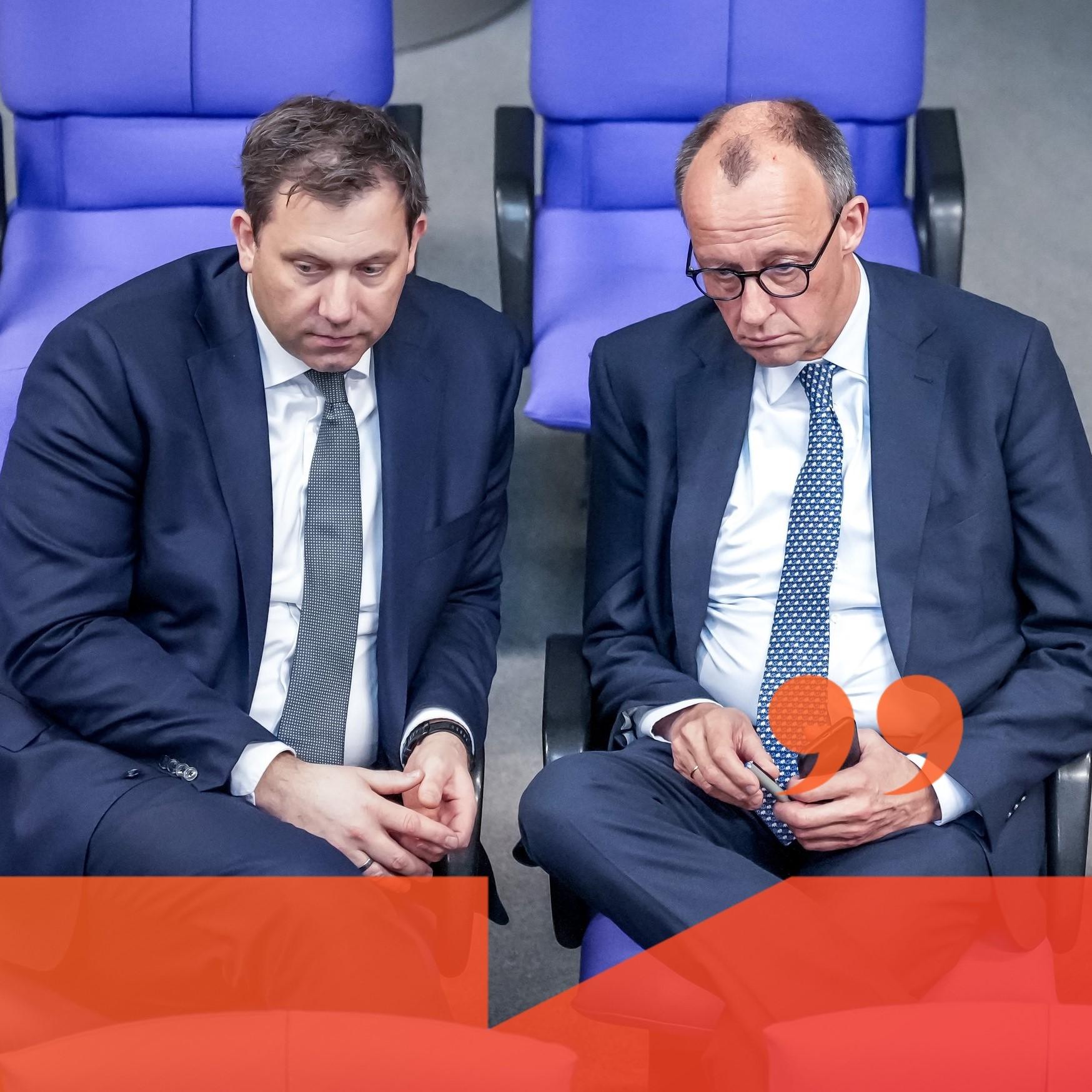 Lars Klingbeil und Friedrich Merz sitzen im Bundestag alleine in einer Sitzreihe mit strengen Blick