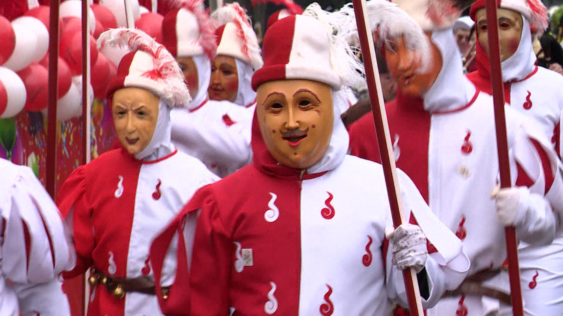 Rot-weiß gekleidete Schembartläufer mit Holzmasken vor dem Gesicht.