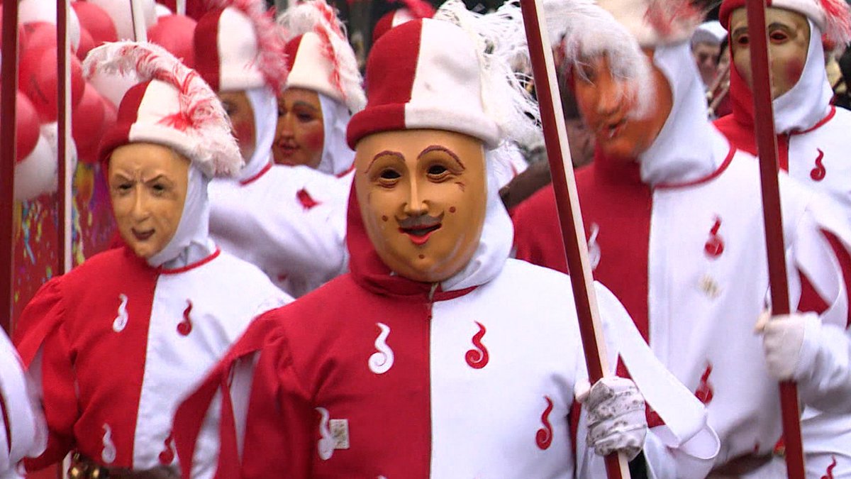 Rot-weiß gekleidete Schembartläufer mit Holzmasken vor dem Gesicht.
