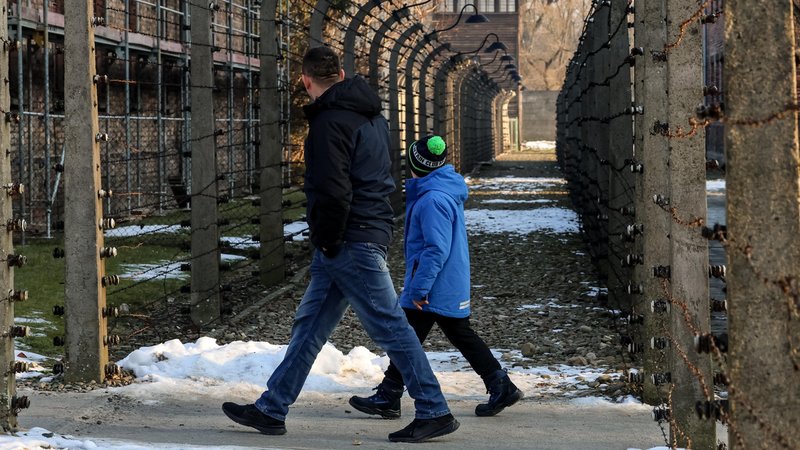Ein Mann und ein junge laufen durch das KZ Auschwitz. | Bild: picture alliance / Sipa USA | SOPA Images Ein Mann und ein junge laufen durch das KZ Auschwitz.