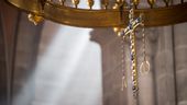 Ein Kreuz hängt an einem Leuchter im Altarbereich des Bamberger Doms.  | Bild:dpa-Bildfunk/Daniel Vogl