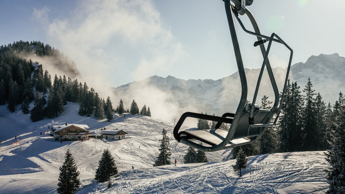 Ein Sessellift vor verschneitem Bergpanorama in den bayerischen Alpen