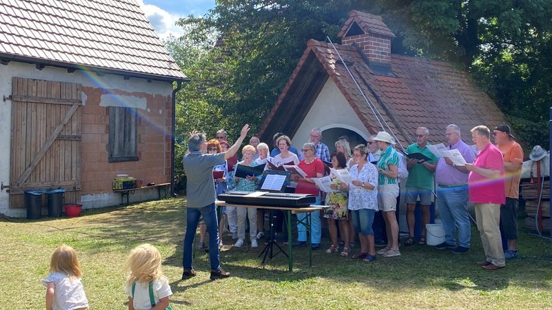 Singende Menschen stehen vor einem alten Backofen. | Bild: BR / Anja Bischof Singende Menschen stehen vor einem alten Backofen.