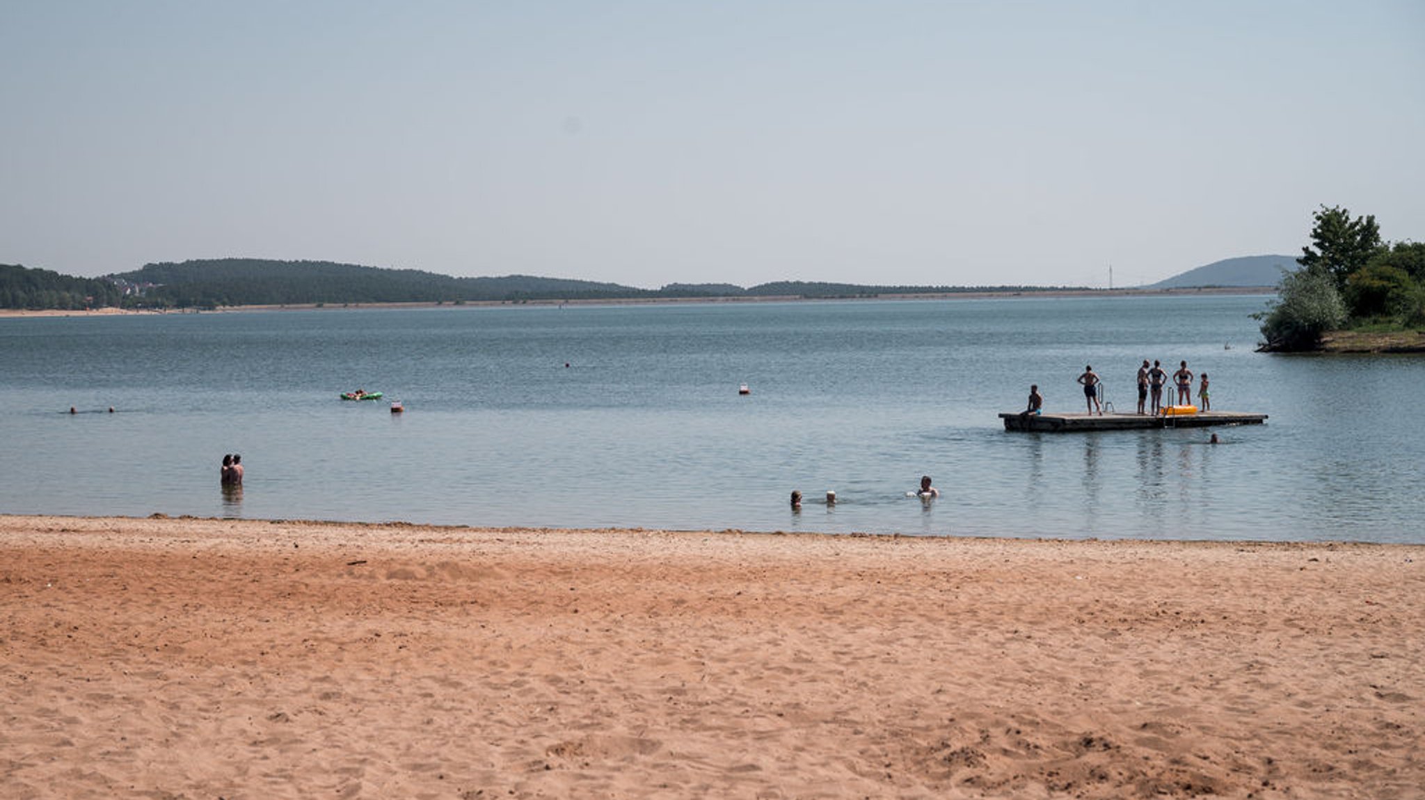 ARCHIV - 25.07.2022, Bayern, Pleinfeld: Badegäste sind im Wasser und auf einem schwimmenden Floß. Am Badestrand Ramsberg am Großen Brombachsee sind am Vormittag schon einige Badegäste anzutreffen. (zu dpa: «Schwimmer bei erneutem Wels-Angriff im Brombachsee verletzt») Foto: Daniel Vogl/dpa +++ dpa-Bildfunk +++