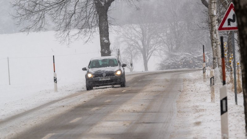 Auto auf verschneiter Straße in Bayern