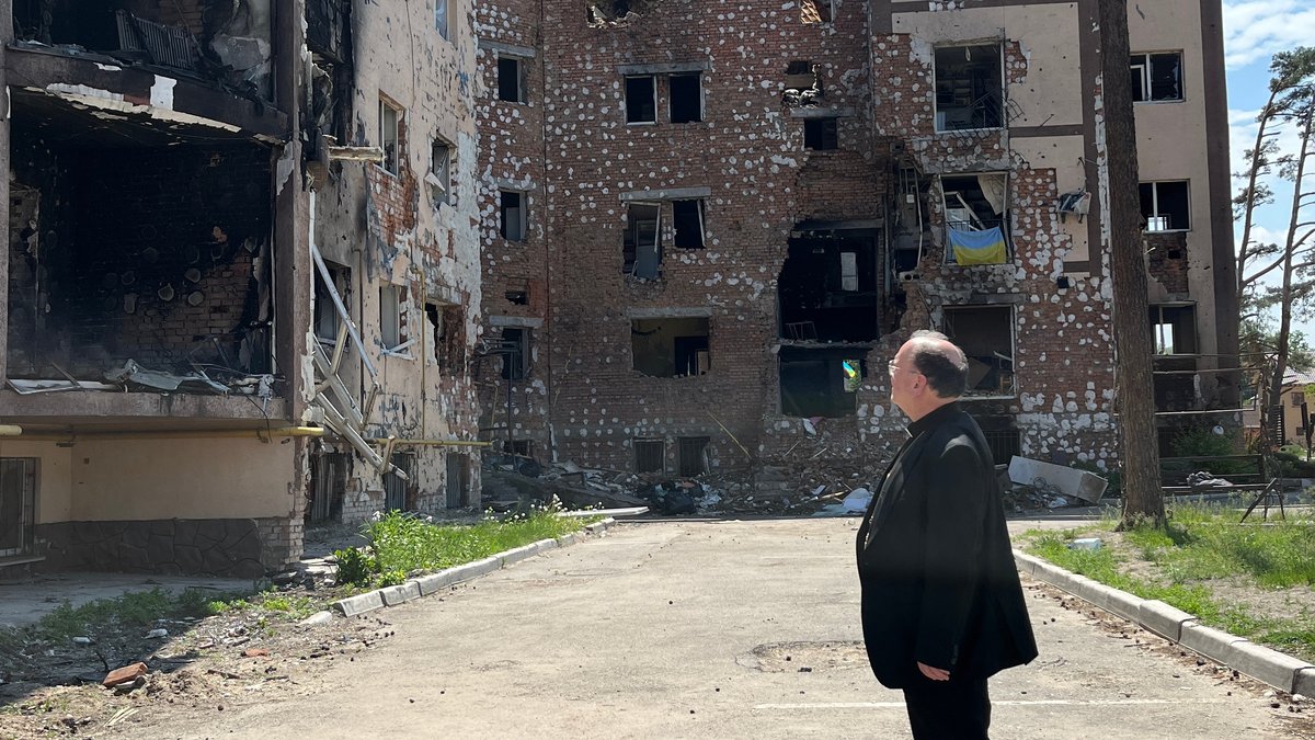 Der Augsburger Bischof Meier in der Ukraine vor zerbombten Häusern in Irpin.