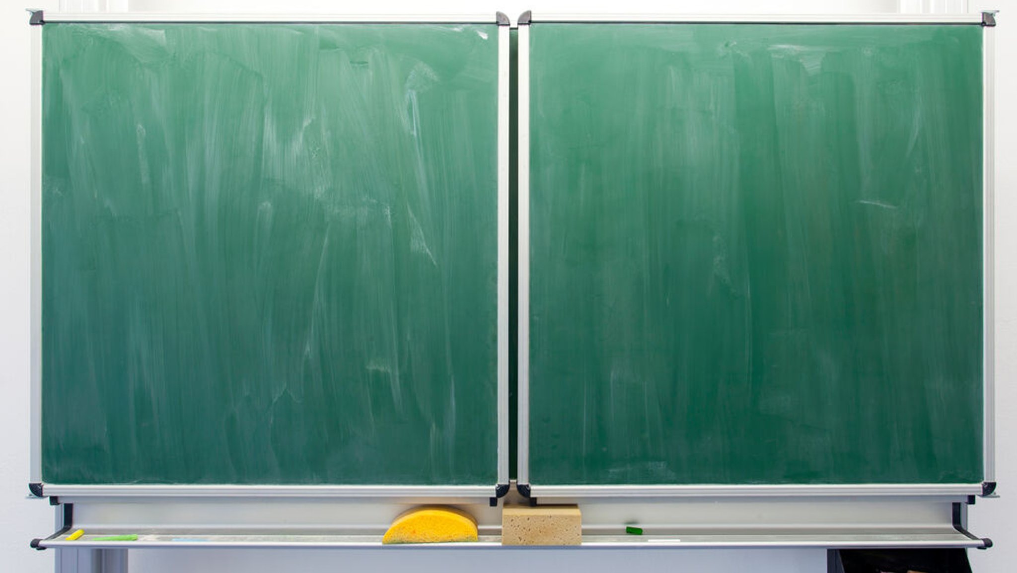 Eine leer gewischte Schultafel mit Schwämmen.