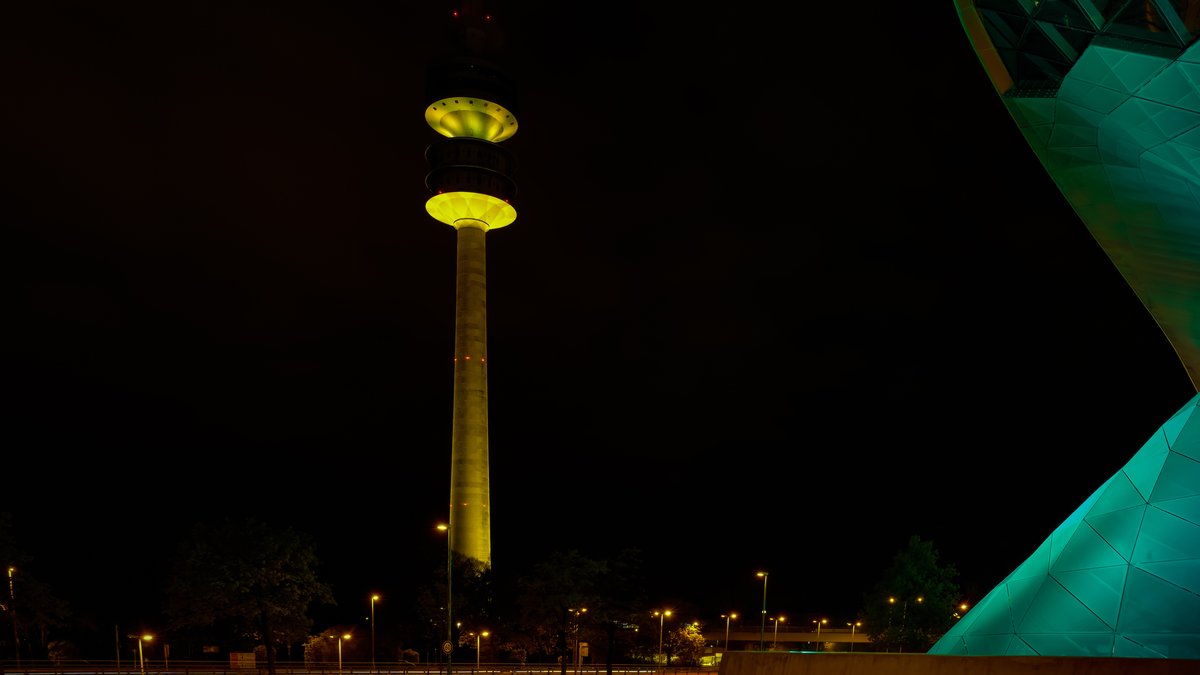 Münchner Olympiaturm, angestrahlt in den Münchner Stadtfarben schwarz und gelb