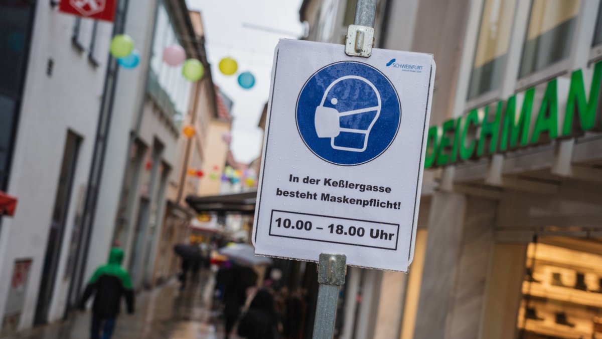 In einer schmalen Gasse in der Schweinfurter Innenstadt ist ein Schild aufgestellt, das auf die Maskenpflicht hinweist.