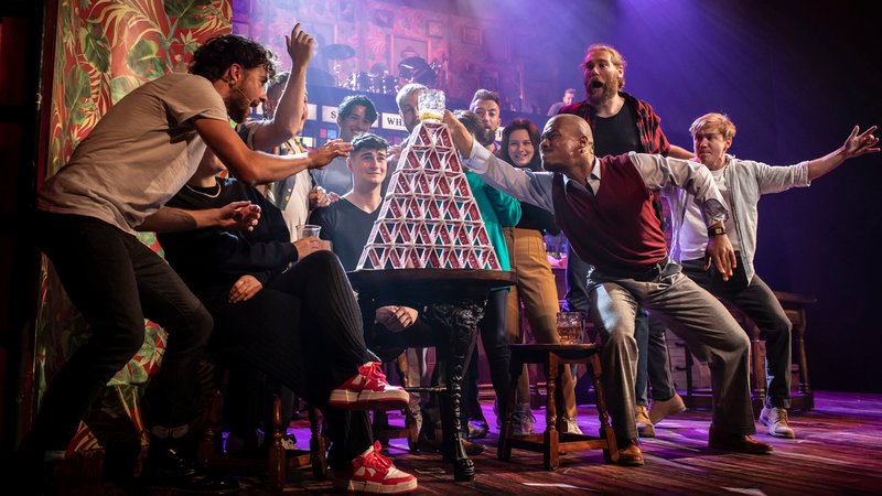 Ensemble-Mitglieder bauen einen Turm aus Spielkarten | Bild: Helen Maybanks/Deutsches Theater München Ensemble-Mitglieder bauen einen Turm aus Spielkarten