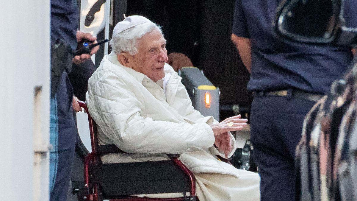 Der emeritierte Papst Benedikt XVI wird mit einem Rollstuhl in einen Bus geschoben. 