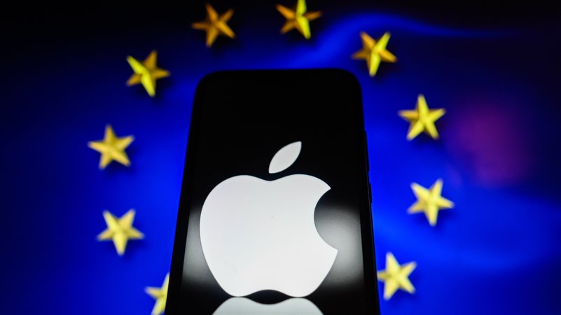 Das Apple-Logo auf einem Smartphone, im Hintergrund die Flagge der EU
