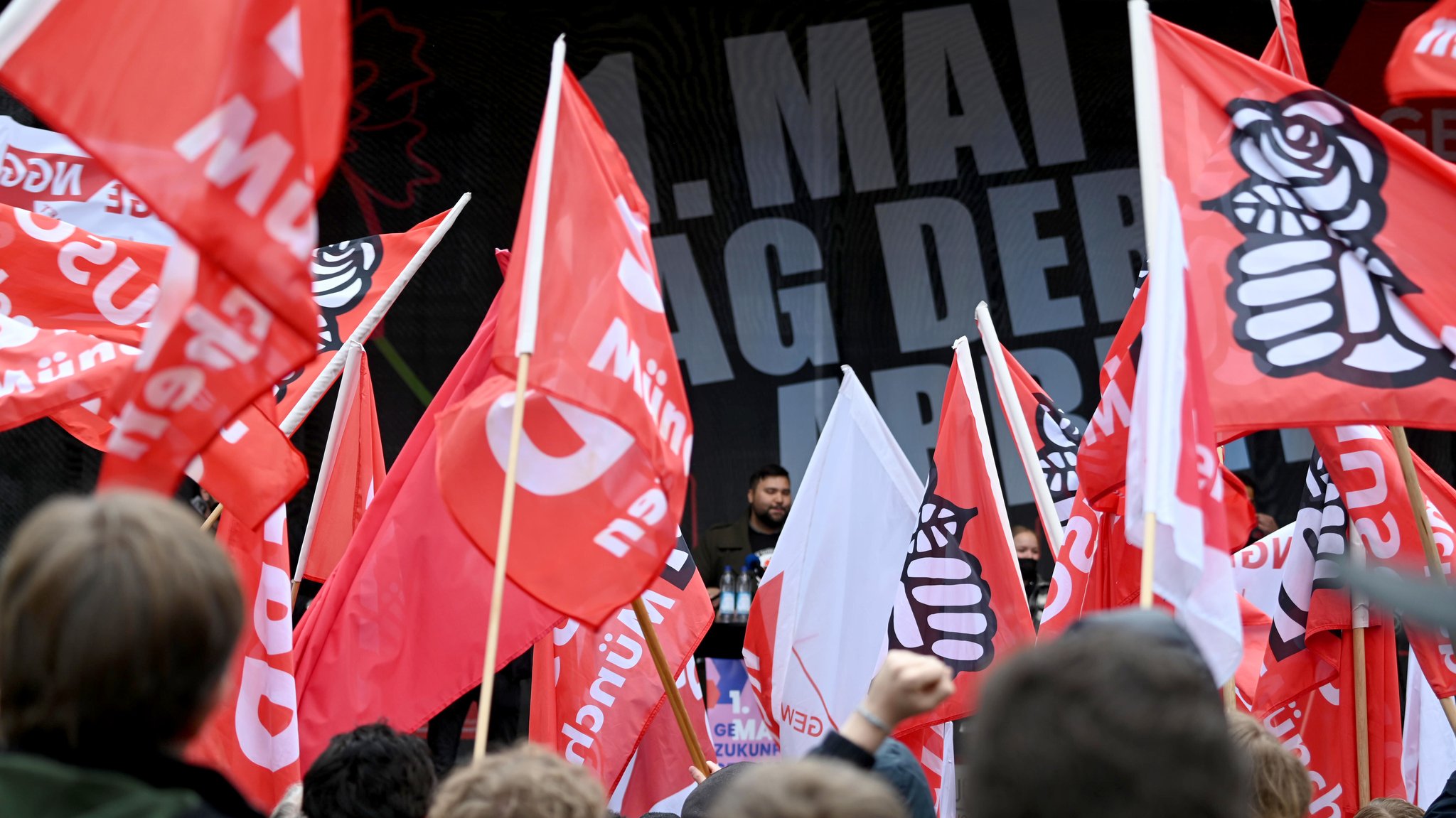Eine Gruppe von Menschen schwenkt am 1. Mai Fahnen auf dem Münchner Marienplatz.