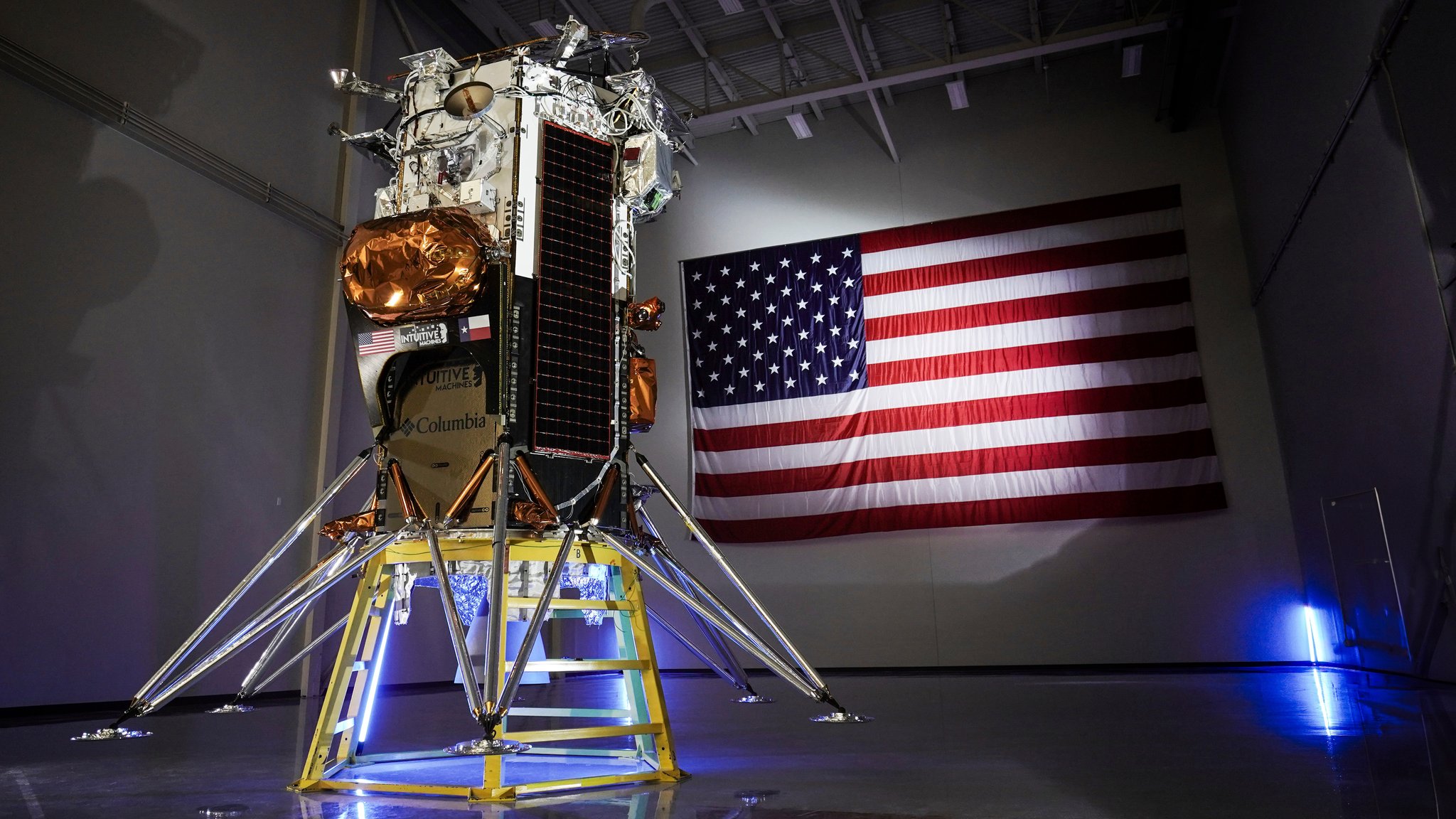 Eine etwa telefonzellen-große Box mit dünnen Beinen und Solarpanelen an der Seite. Im Hintergrund eine riesige US-Flagge.