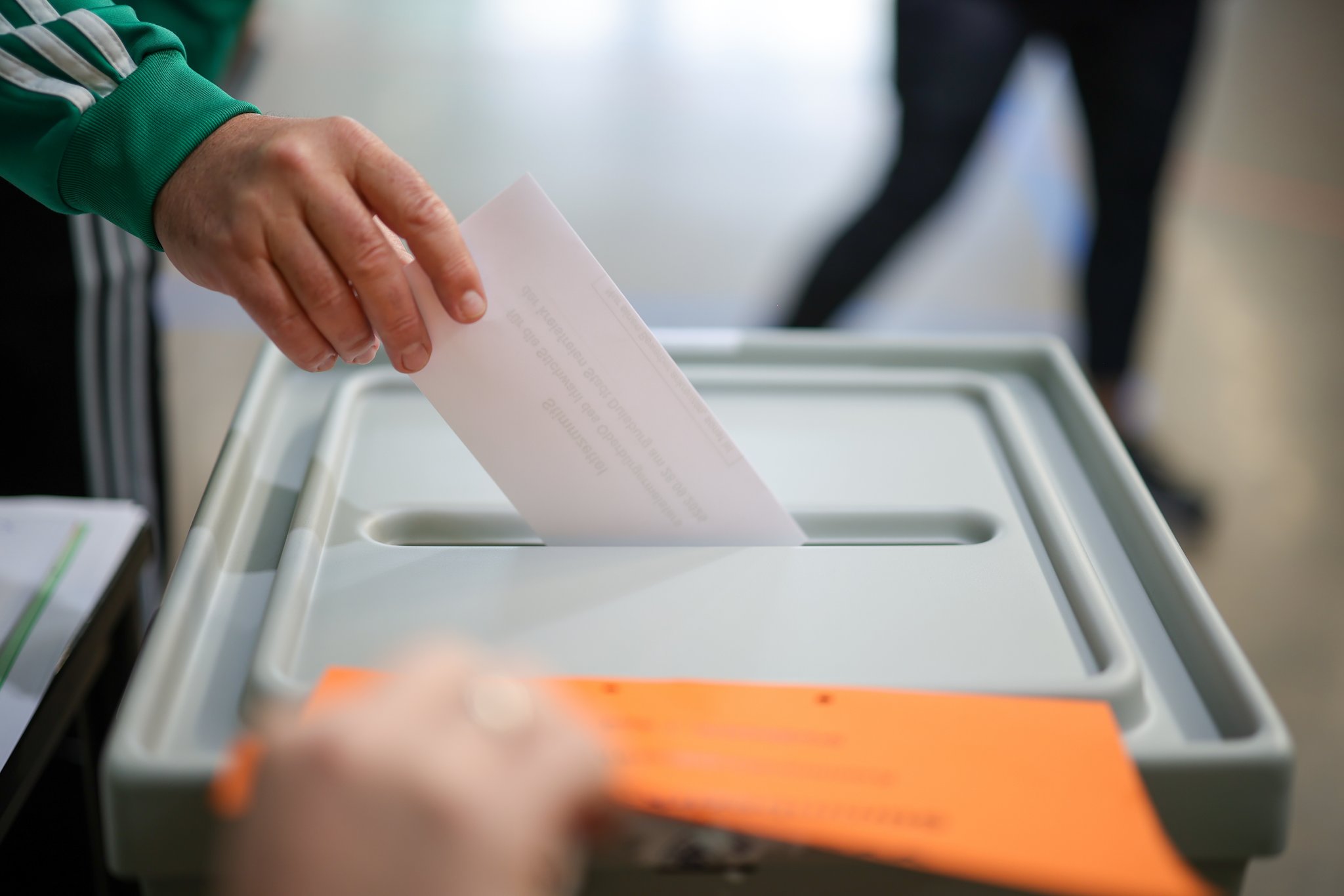 Eine Person wirft ihren Wahlzettel zur Oberbürgermeister-Stichwahl in die Wahlurne. 