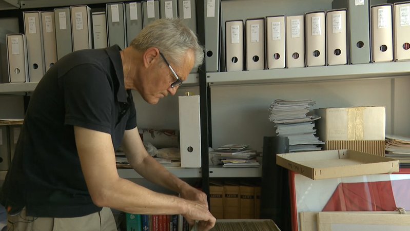Club-Historiker Bernd Siegler in einem Büro. Er sucht in einem Karton mit Karteikarten.
