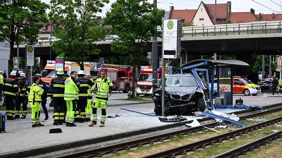 Einsatzkräfte stehen bei dem Unfallfahrzeug und einer zerstörten Haltestelle.
