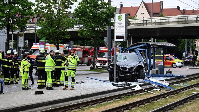 Einsatzkräfte stehen bei dem Unfallfahrzeug und einer zerstörten Haltestelle. | Bild: dpa-Bildfunk/Felix Hörhager Einsatzkräfte stehen bei dem Unfallfahrzeug und einer zerstörten Haltestelle.
