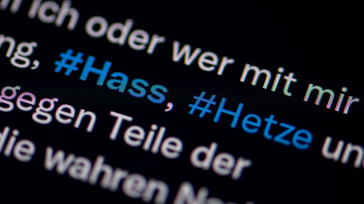 Auf dem Bildschirm eines Smartphones sieht man die Hashtags Hass und Hetze in einem Twitter-Post 