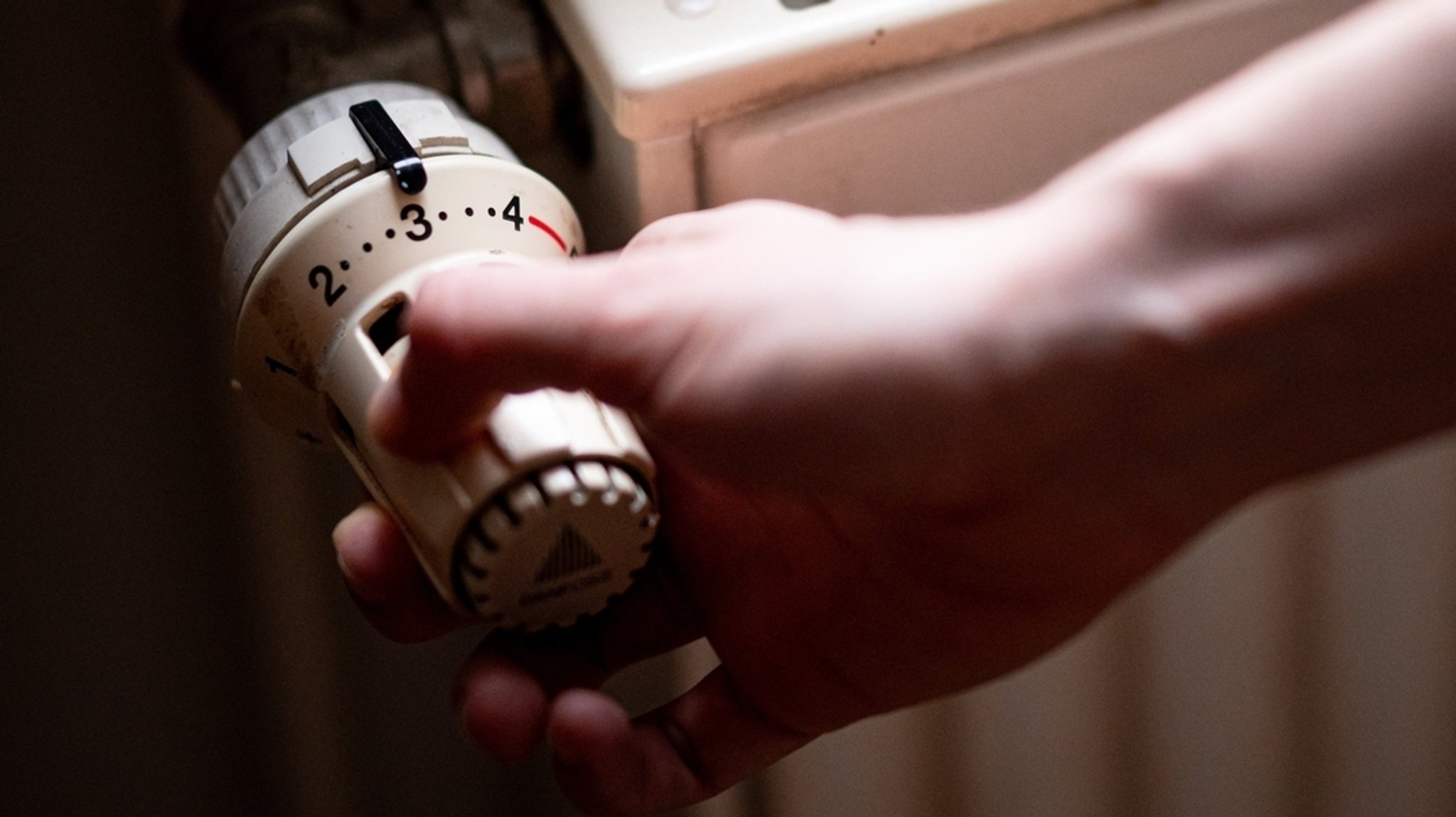 Eine Person benutzt einen alten Heizkörper in einer Altbauwohnung. 