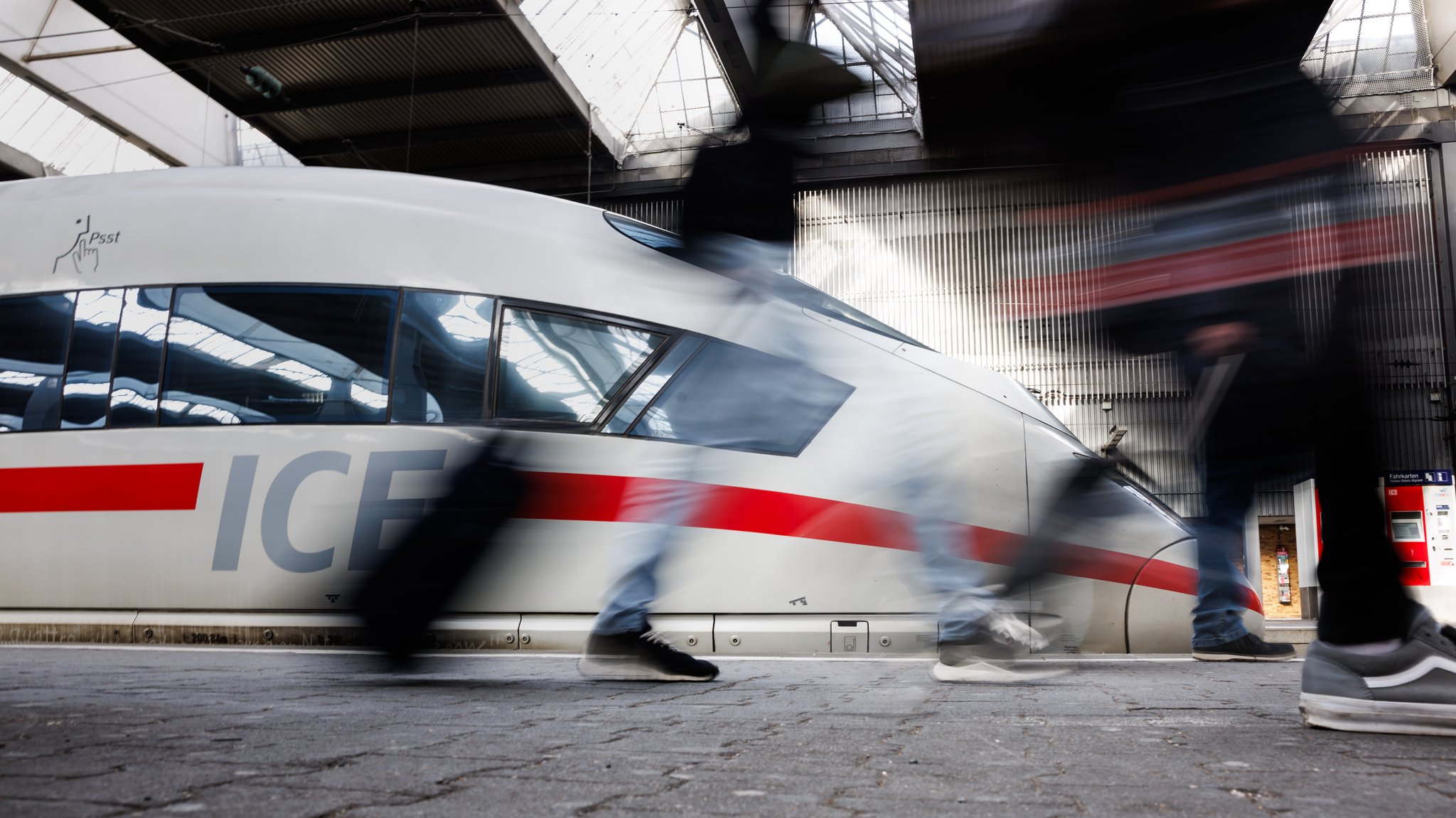 Reisende gehen an einem Bahnsteig an einem ICE der Deutschen Bahn am Hauptbahnhof von München vorüber.