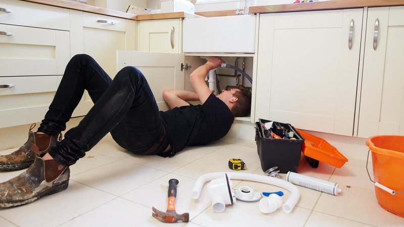 Symbolbild: Ein Handwerk liegt unter einem Abflussrohr und versucht, es zu reparieren. | Bild: picture alliance / Shotshop | Monkey Business 2 Symbolbild: Ein Handwerk liegt unter einem Abflussrohr und versucht, es zu reparieren.