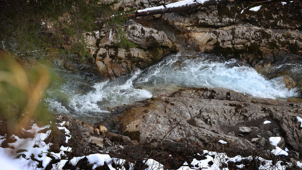 Wasser rauscht ein Bachbett hinab.