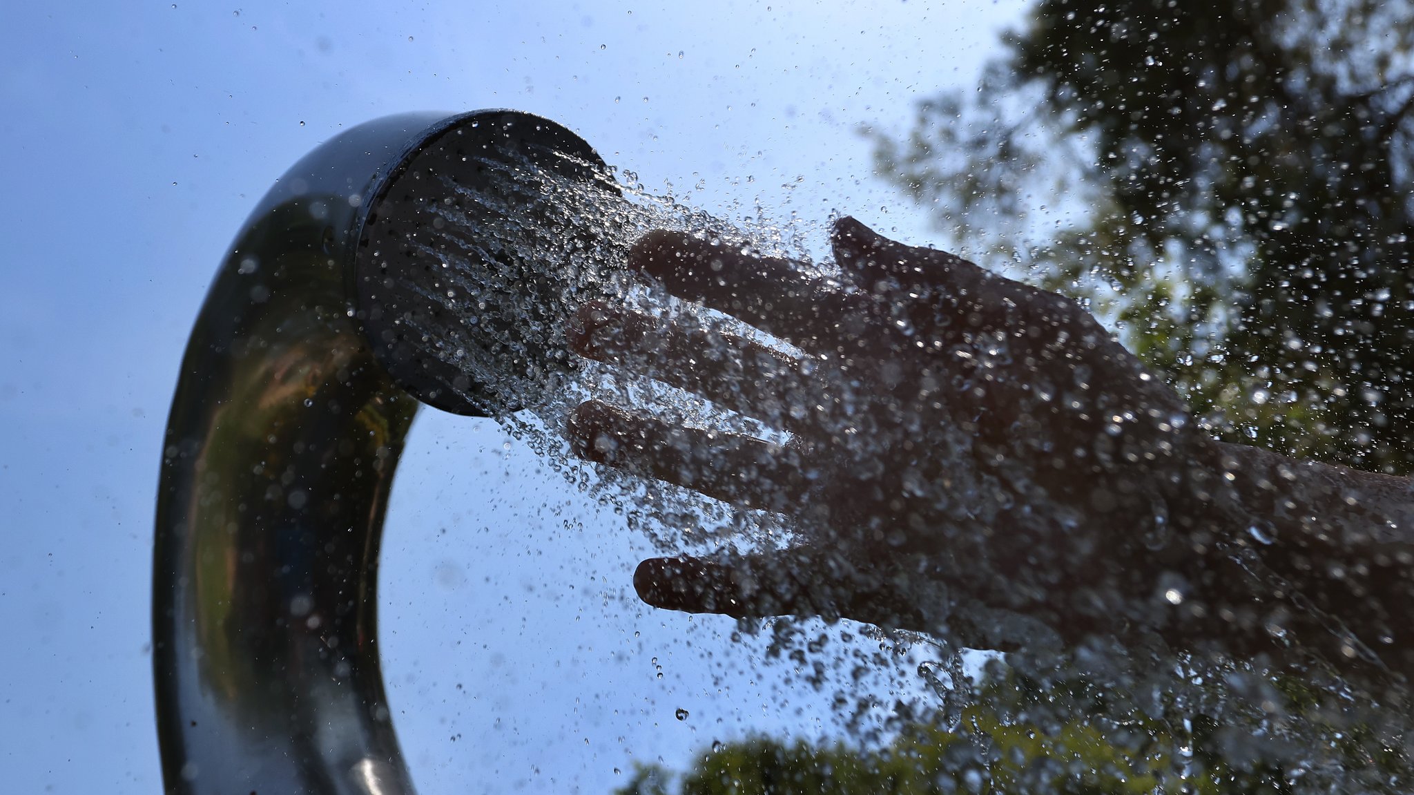 Ein Besucher eines Strandbades kühlt seine Hand unter einer Dusche.