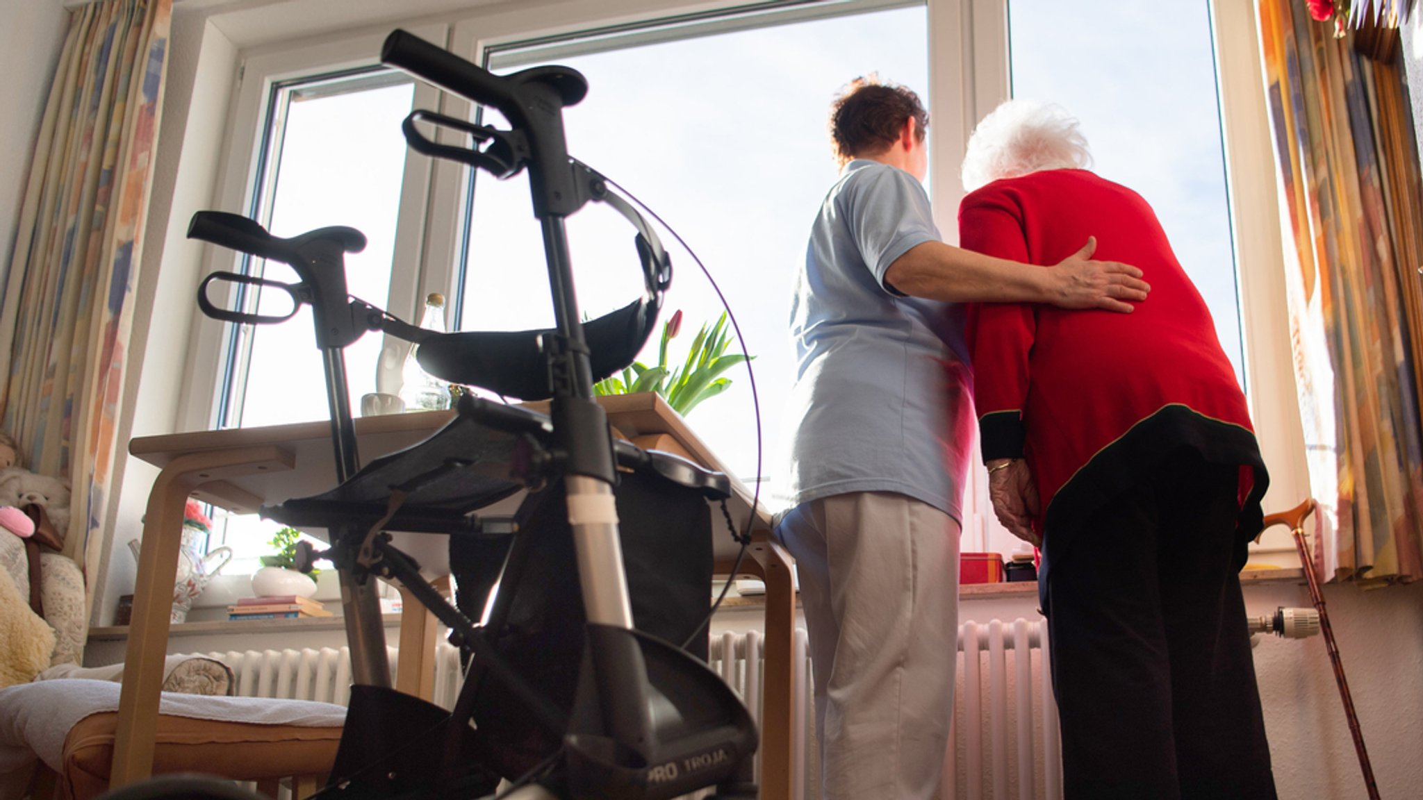 Eine Pflegerin blickt gemeinsam mit einer Patientin aus dem Fenster