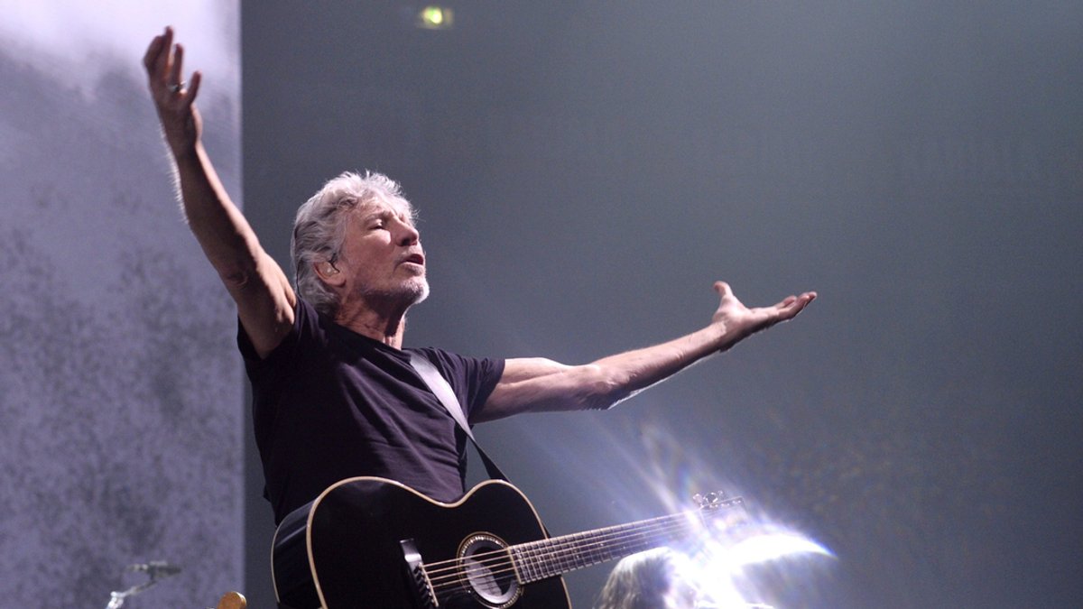 Roger Waters steht mit seiner Gitarre auf einer Bühne.