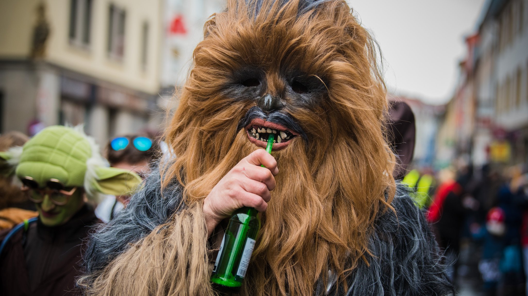 Ein als Chewbacca verkleideter Besucher eines Faschingsumzugs trinkt Bier.