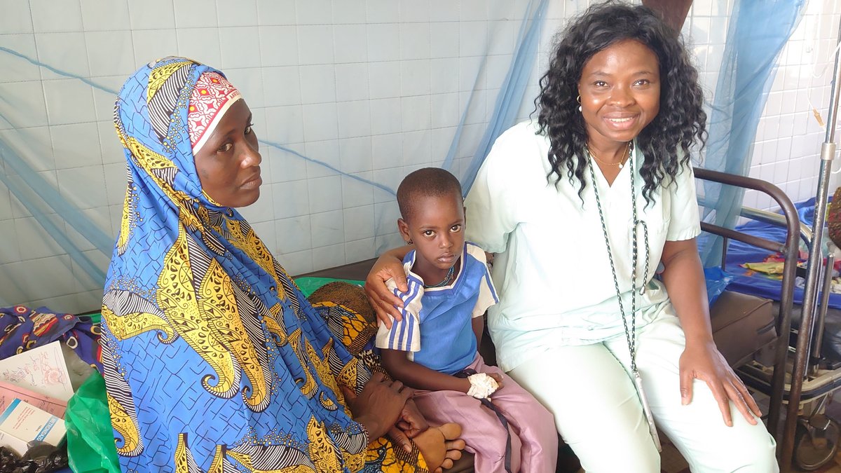 Rali Guemedji, die  Gründerin von Fi Bassar, sitzt bei einer Mutter und ihrem kranken Kind auf dem Krankenhausbett.