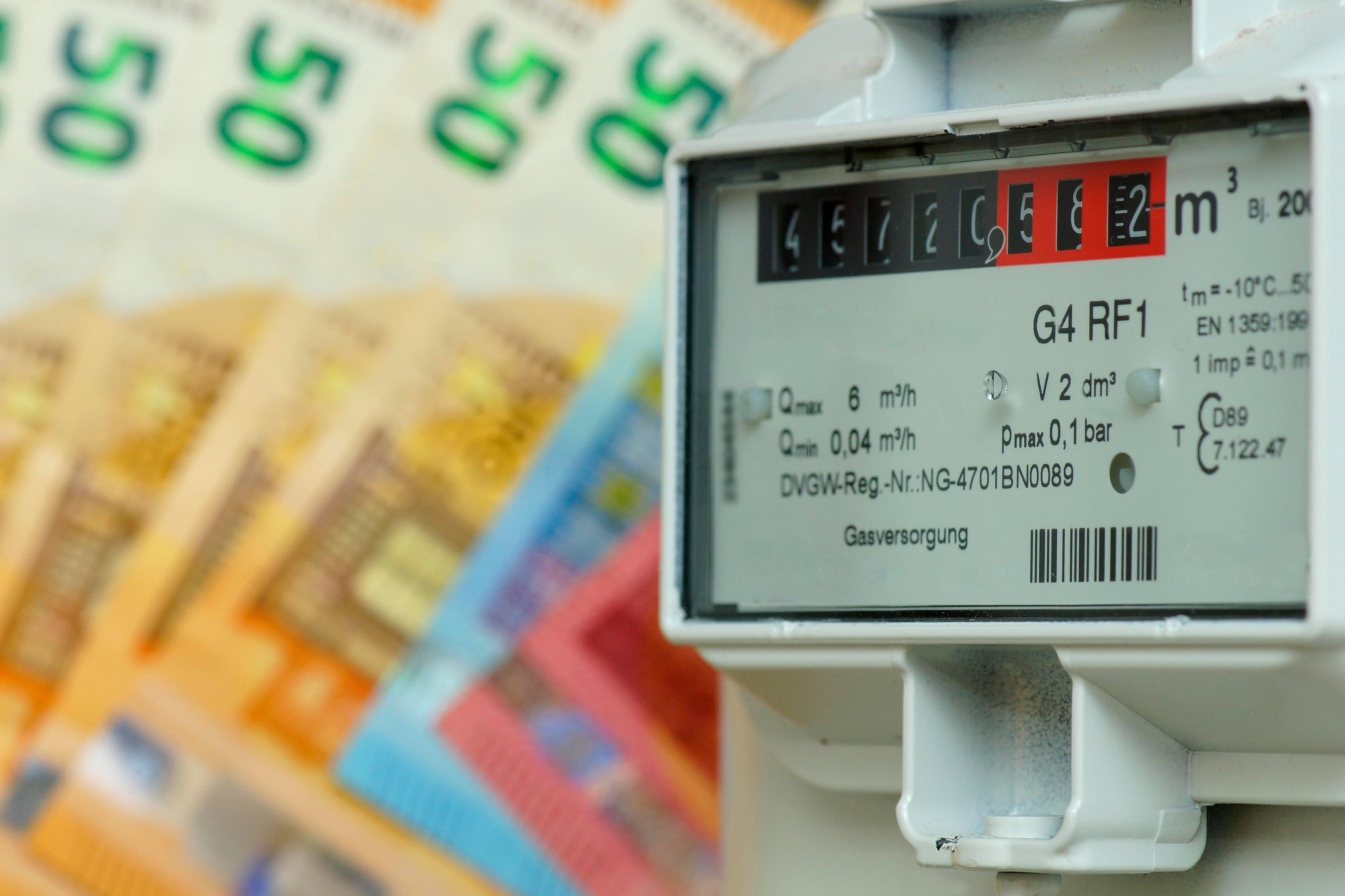 Ein Gaszähler, im Hintergrund sieht man unscharf Geldscheine