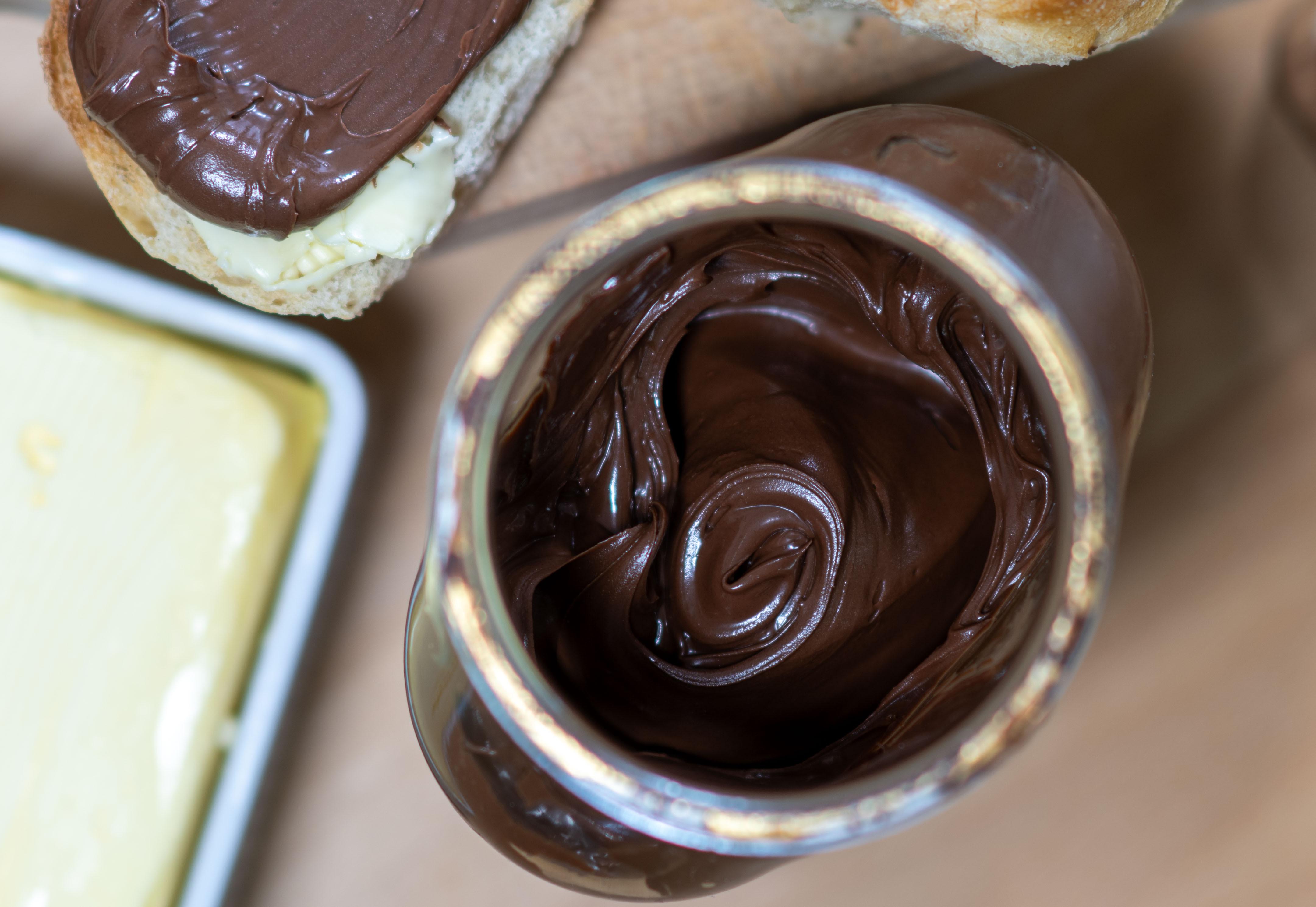 Ein Glas Schokocreme mit einer Butterschale und einem bestrichenen Brot (Symbolbild)