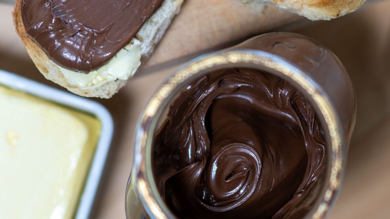 Ein Glas Schokocreme mit einer Butterschale und einem bestrichenen Brot (Symbolbild) | Bild: picture alliance/dpa | Hendrik Schmidt Ein Glas Schokocreme mit einer Butterschale und einem bestrichenen Brot (Symbolbild)