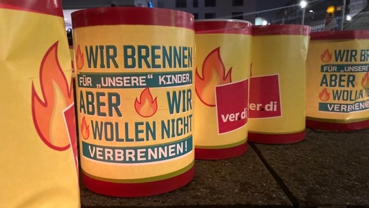 Rot-gelbe Verdi-Laternen mit der Aufschrift: "Wir brennen für 'unsere' Kinder, aber wir wollen nicht verbrennen."