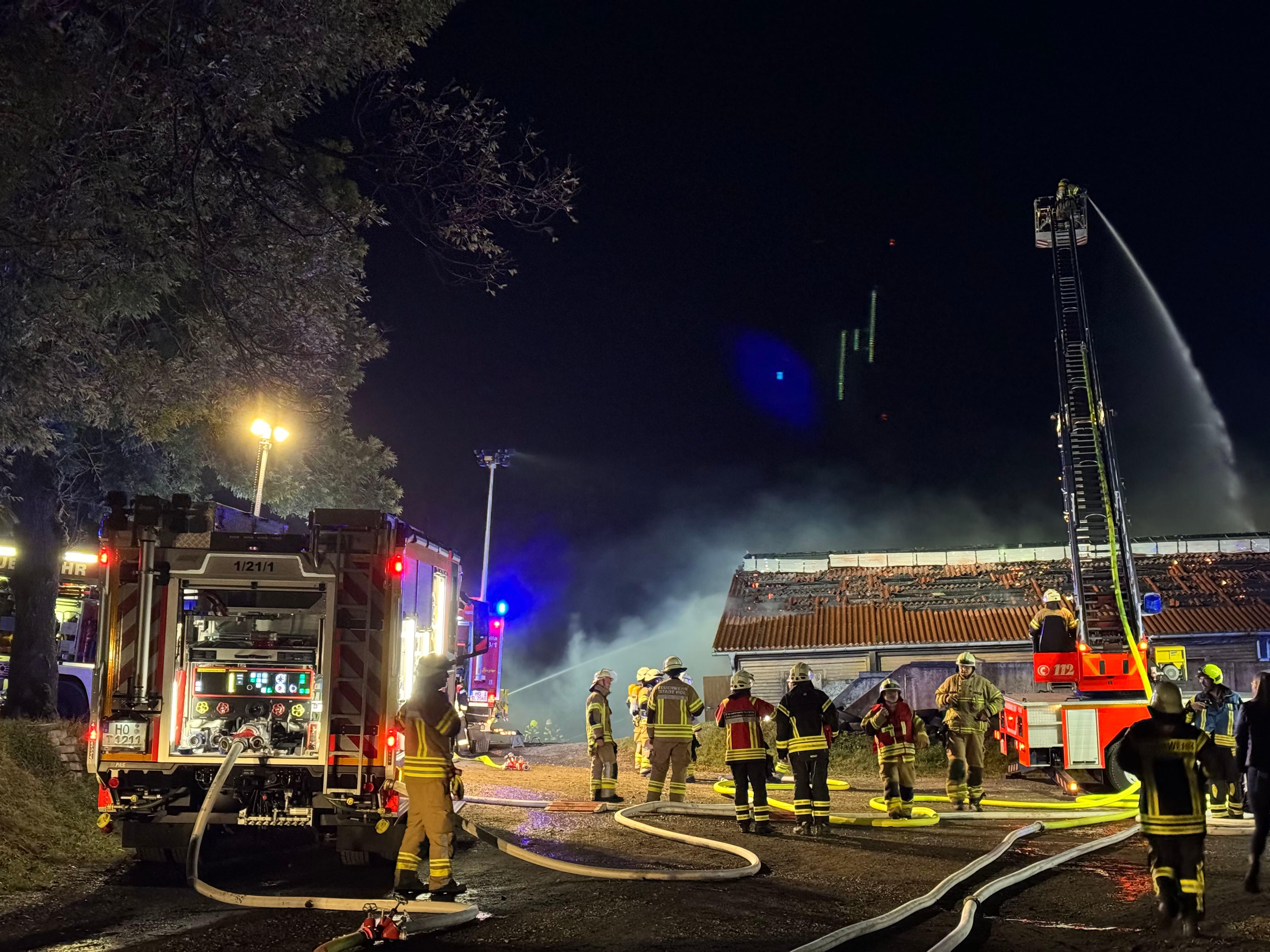 Einsatzkräfte der Feuerwehr vor einem brennenden Stall.