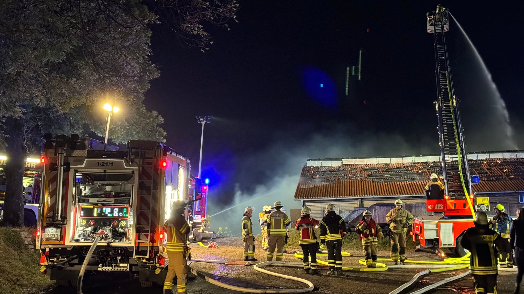 Einsatzkräfte der Feuerwehr vor einem brennenden Stall.