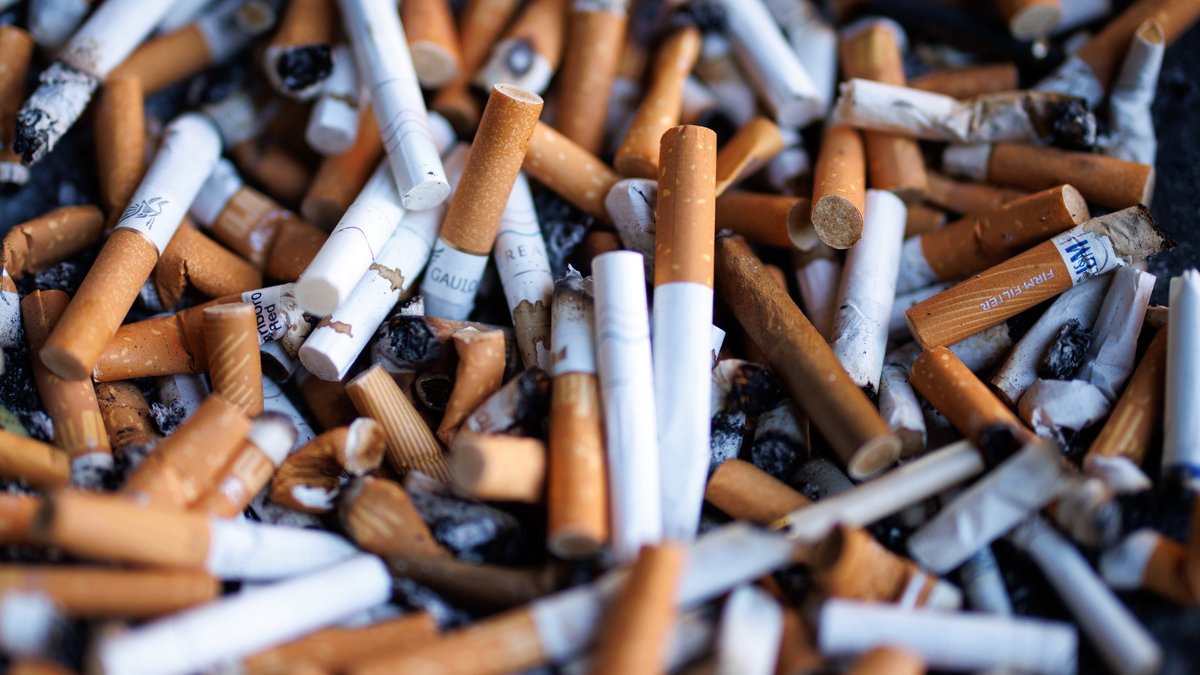 Zahlreiche Zigarettenstummel liegen in einem Aschenbecher an einem öffentlichen Gebäude in München.  