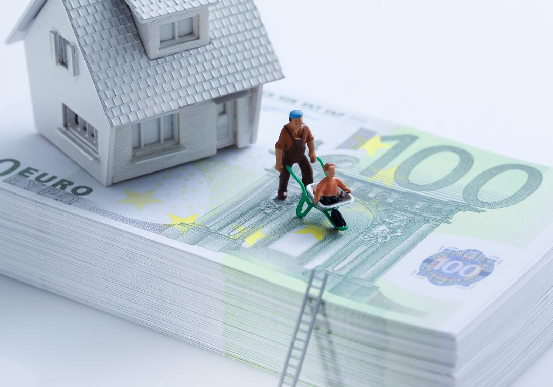 Hausmodell und Figuren auf Stapel Euroscheine