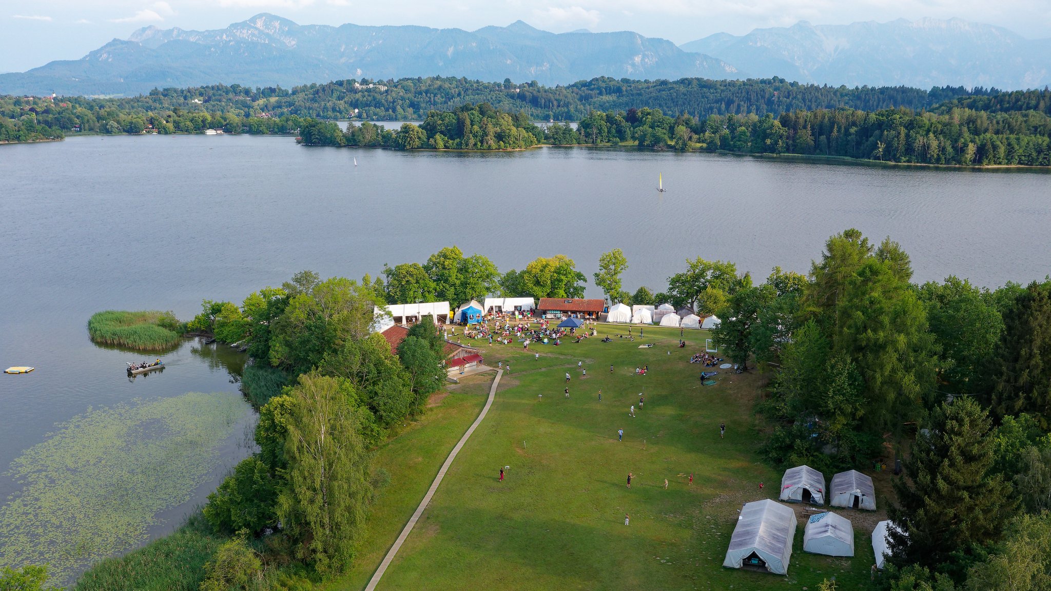 Blick über die Halbinsel Lindenbichl am Staffelsee mit Zeltstadt in die bayerischen Berge.