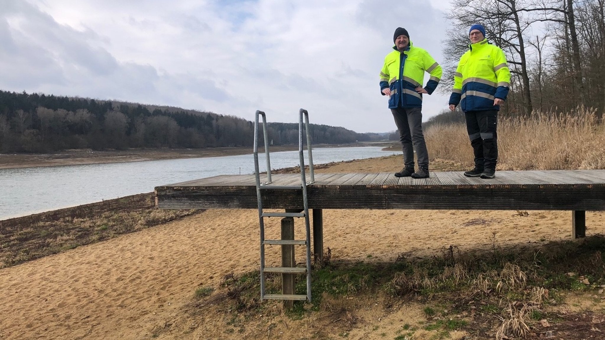 Zwei Hydrologen stehen auf einem Steg über einer Sandbank am Ellertshäuser See