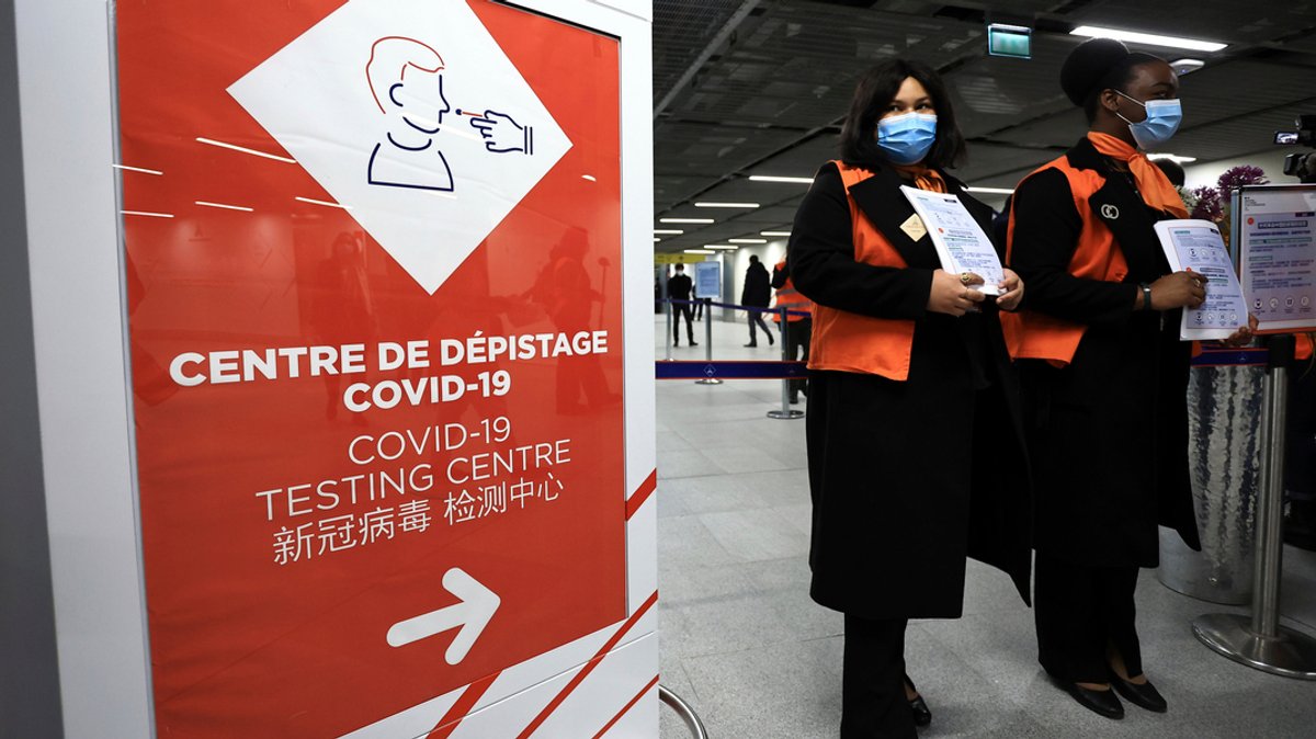 Zwei Flughafenmitarbeiterinnen warten auf Passagiere aus China vor einem Coronavirus-Testbereich auf einem Flughafen in Frankreich