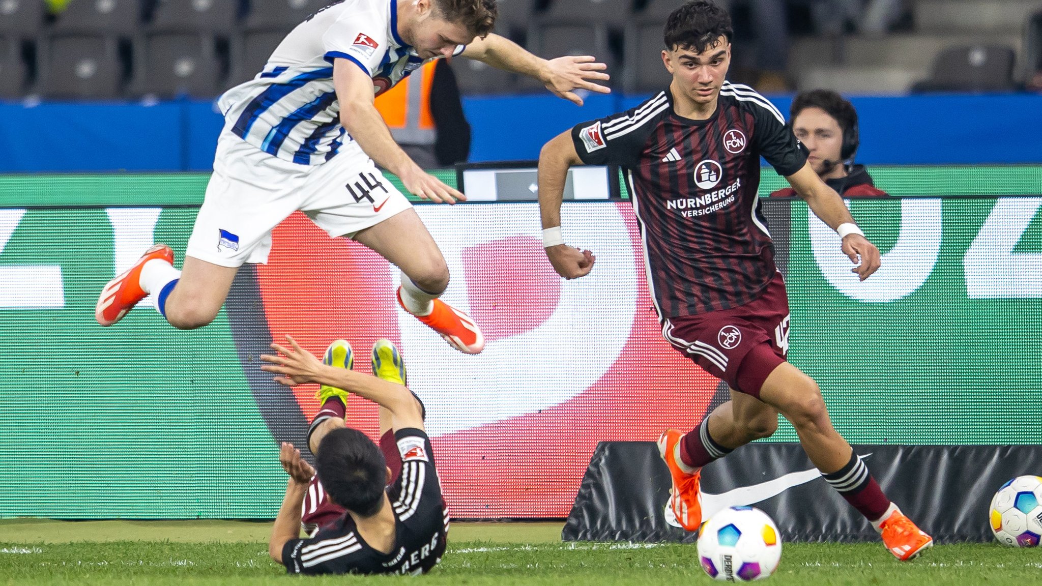 30.03.2024, Berlin: Fußball: 2. Bundesliga, Hertha BSC - 1. FC Nürnberg, 27. Spieltag, Olympiastadion. Berlins Linus Gechter (l-r) springt über Jens Castrop von 1. FC Nürnberg im Kampf gegen Can Uzun. 