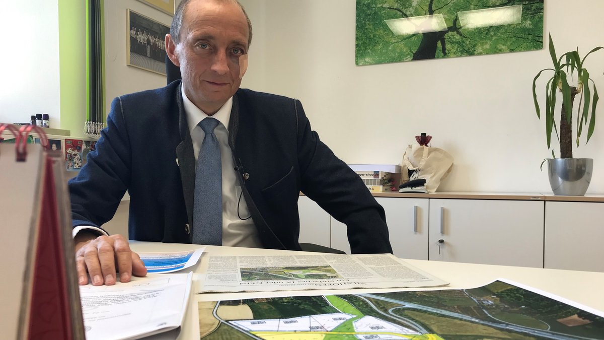 Windorfs Bürgermeister Franz Langer sitzt vor dem Plan zum Gewerbegebiet