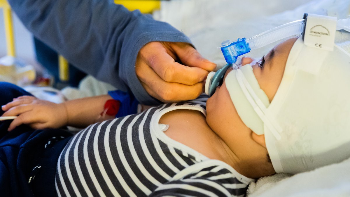 Säugling mit Schnuller und Sauerstoffschlauch im Krankenhausbett